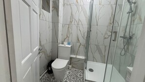 Un baño con inodoro, bidé y cabina de ducha.