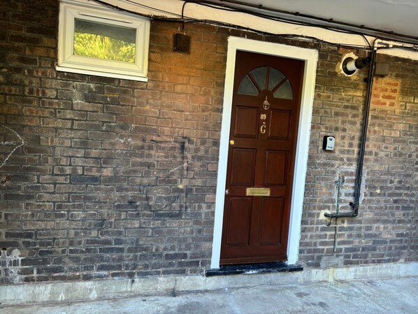 A brick building with a brown door, a small window, and a mailbox.