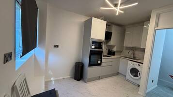 A modern kitchen with a built-in oven, microwave, and washing machine.