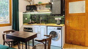 Une cuisine compacte équipée d’un lave-linge, d’un four à micro-ondes et d’une table à manger en bois avec des chaises.