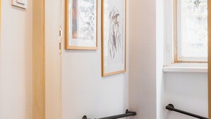 Un couloir aux murs blancs, une porte en bois et une fenêtre donnant sur des arbres.