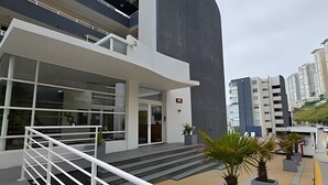 A modern building with a large glass facade, a white exterior, and a set of stairs leading to the entrance. - Oceana Suites EuroMarina II (Viña del Mar)