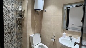 Une salle de bain avec des toilettes, un lavabo et une douche.