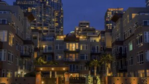 A residential building complex at dusk with illuminated windows and a gated entrance. - Puget Sound Views Elegant 2BR Walk to Pike Place (Seattle)