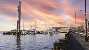 A marina with boats docked, a tall structure on the left, and a waterfront promenade. - Puget Sound Views Elegant 2BR Walk to Pike Place (Seattle)