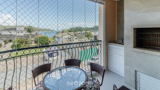 A balcony with a glass table and wicker chairs, overlooking a residential area and a body of water. - Apt w/ BBQ & View, 130m From Beach Rsd0202 (Porto Belo)