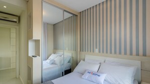 A hotel room with a large bed, a bedside table, a mirror, and a striped wall. - Apt w/ BBQ & View, 130m From Beach Rsd0202 (Porto Belo)