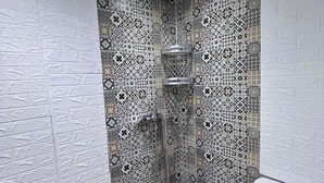 Ein Badezimmer mit gemusterten Fliesen, einer Dusche und einem WC.