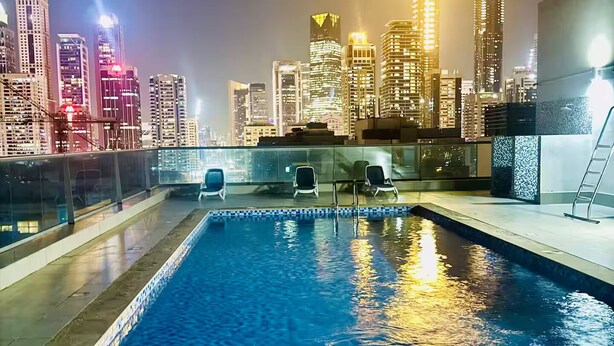 Piscina no terraço com vista para o horizonte urbano, incluindo uma torre do relógio e edifícios modernos.