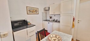 A compact kitchen with white cabinets, a black countertop, a microwave, a sink, and a small dining table. - Apartment 'Serristori With a View' with Wi-Fi and Air Conditioning (Firenze)