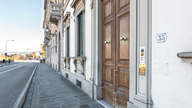 Vista de carrer amb un edifici que destaca per una gran porta de fusta, una placa amb un número i una vorera.