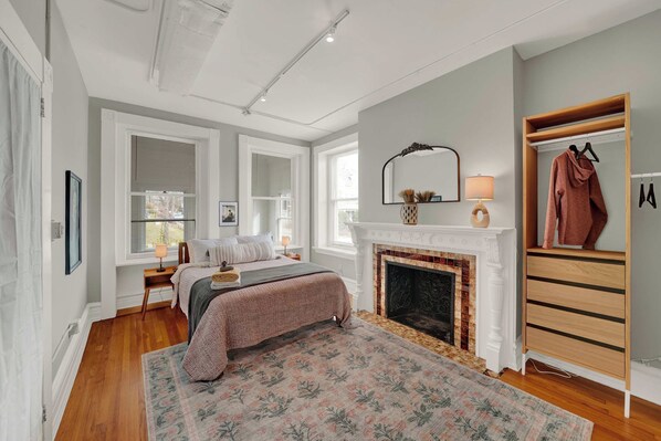 A bedroom with a bed, a fireplace, a mirror, and a wardrobe. - Huge 1st floor Historic Apartment Soaring Ceilings (Wilmington)