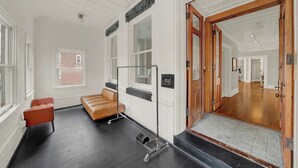 En hotellobby med en lädersoffa, en trädörr och utsikt över korridoren.