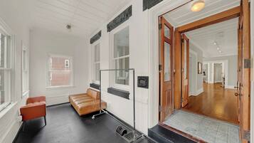 Un hall d’hôtel avec un canapé en cuir, une porte en bois et une vue sur le couloir.