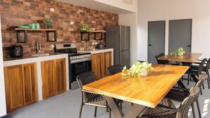 Une cuisine moderne avec des meubles en bois, un grand îlot central et un coin repas comprenant une table et des chaises en bois.
