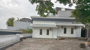 A building with a flat roof, a paved courtyard, and a white exterior. - Hotel O 95063 Afifah Syariah Guest House Manado (Manado)