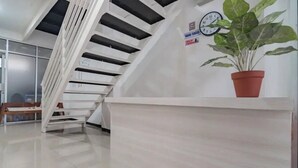 A modern reception area with a staircase, a clock, and a potted plant. - Hotel O 95063 Afifah Syariah Guest House Manado (Manado)