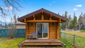 Eine Blockhütte mit Veranda, einer Schiebetür und einem kleinen Tisch mit Stuhl.