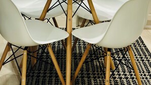 A dining area with a round table, four white chairs, a patterned rug, and a kitchen in the background. - Family style cozy living in friendly surroundings (Ajax)