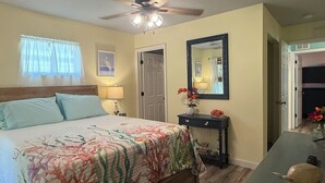 Un dormitorio con cama, ventilador de techo, mesita de noche, cómoda y espejo.