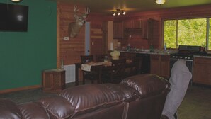 A cabin interior with a dining area, kitchen, and a leather couch. - Twisted House (Arkansaw)