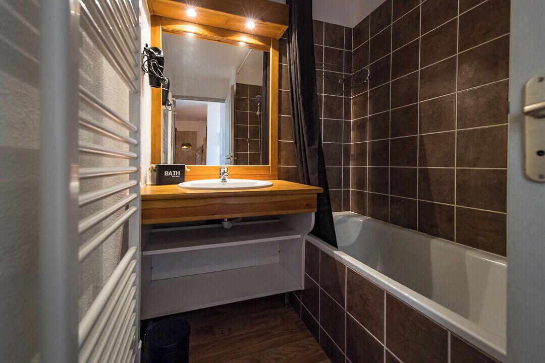 A bathroom with a wooden vanity, a sink, a mirror, and a bathtub.