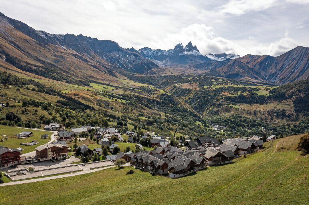 A mountain village with traditional houses, a central square, and a view of the surrounding mountains.