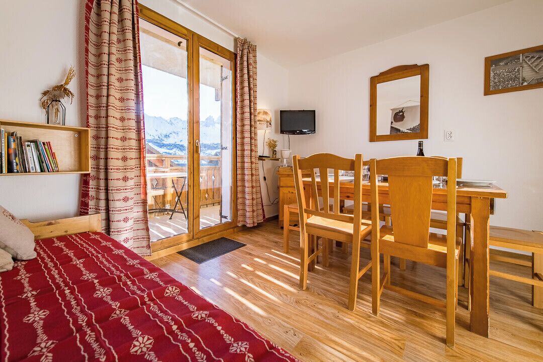 Una camera da letto con un letto, una scrivania in legno, una sedia, un televisore e una finestra con tende.