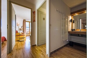 A hallway with wooden flooring leading to a bedroom with a bed and a window. There is a door with a nameplate and a radiator in the bathroom. - Apartment for 4 - 6 people in Albiez-Montrond (Albiez-Montrond)