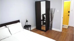 Une chambre à coucher avec un lit, une armoire, une table de chevet et une porte.