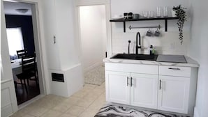 Une cuisine moderne avec des meubles blancs, un robinet noir et un tapis à motifs de marbre.