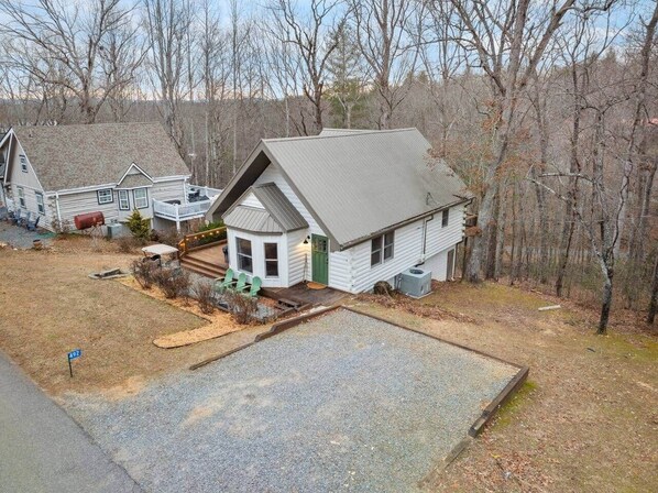 A two-story house with a covered porch, a small deck, and a gravel driveway.