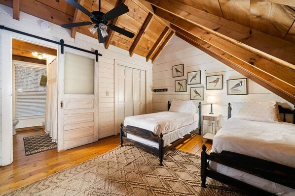 Un dormitorio acogedor en el ático con dos camas, vigas de madera y decoración de pájaros.