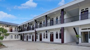 A multi-story building with a central courtyard, balconies, and a staircase leading to the upper floors. - Capital O 95046 Gefa Sleep N Go (Pekanbaru)
