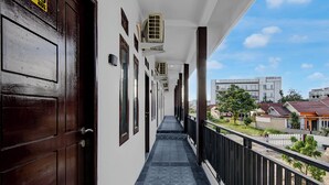 A corridor with a dark wooden door, air conditioning units, and a tiled floor. - Capital O 95046 Gefa Sleep N Go (Pekanbaru)