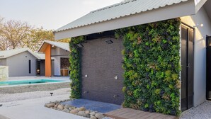 A modern house with a swimming pool, a stone wall, and a wooden deck. - LIV 5 - Studio apartment. Minutes away from the best beaches of Guanacaste. (Lorena)
