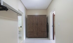 Un couloir avec une grande armoire, une porte sur la droite et un porte-manteau sur la gauche.