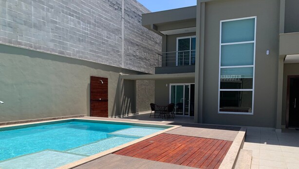 A modern building with a swimming pool, a patio area, and a dining space. - House w/ Pool and Barbecue Grill Thg0006 (Porto Seguro)