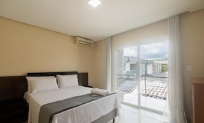Een hotelkamer met een bed, een nachtkastje, een raam met uitzicht en een airconditioning op de muur.