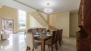 A dining area with a wooden table set for four, surrounded by chairs. A spiral staircase is visible in the background, leading to an upper level. - House w/ Pool and Barbecue Grill Thg0006 (Porto Seguro)