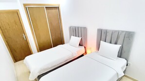 Une chambre d’hôtel avec deux lits simples, une porte en bois et un mur blanc.