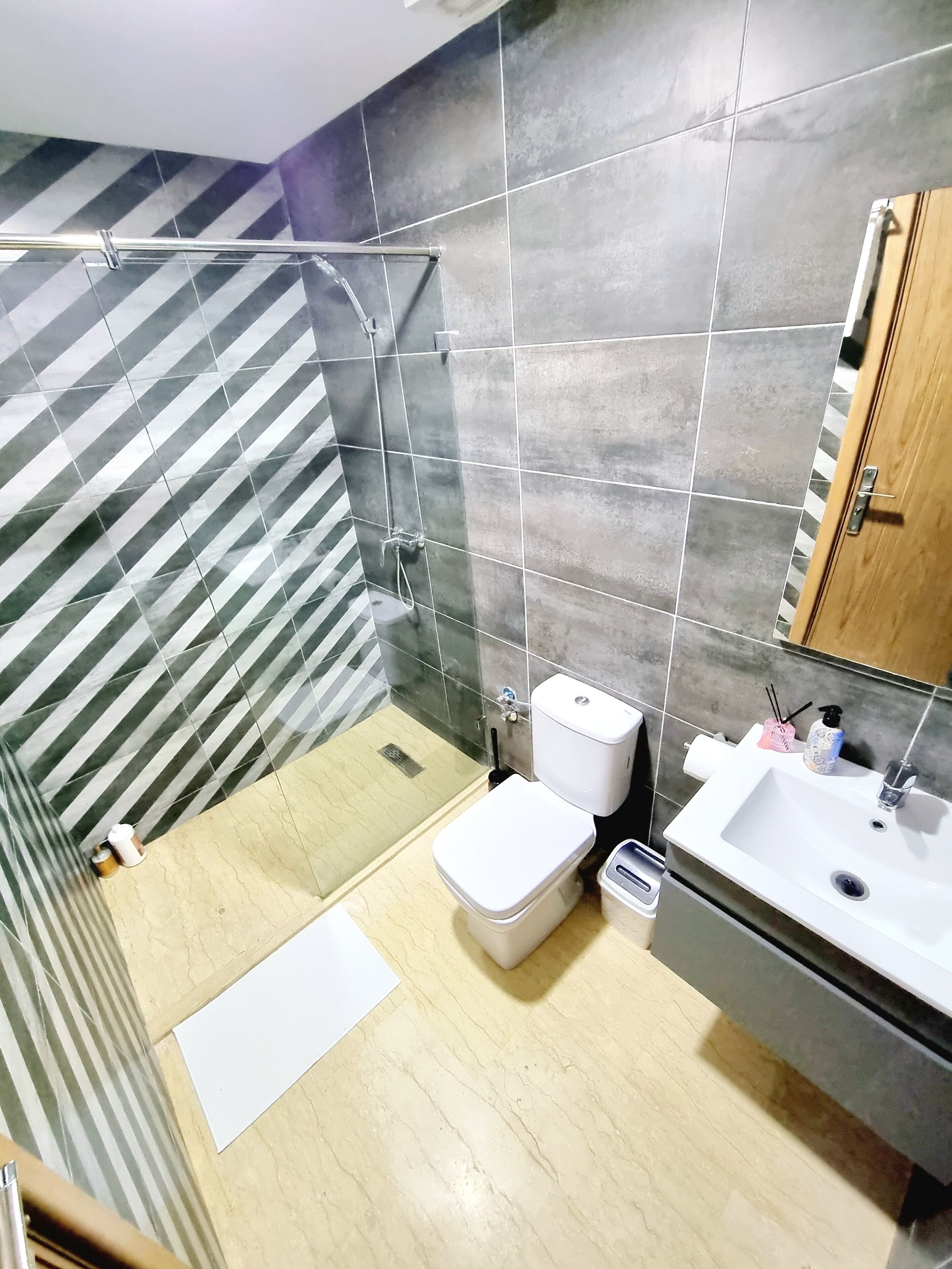 Une salle de bain avec une douche, des toilettes, un lavabo et un mur à rayures.