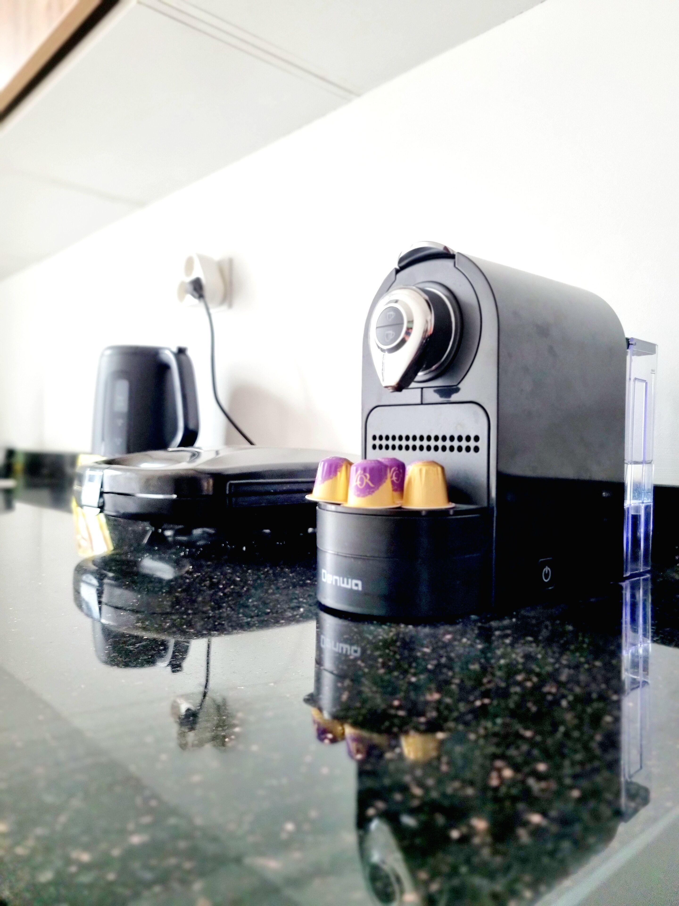 A black portable speaker with a control knob and a cup holder on a glass table.