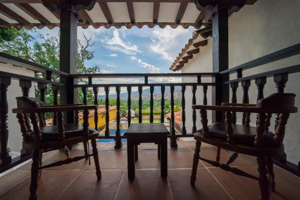 Un balcon avec deux chaises en bois et une petite table, offrant une vue sur un paysage pittoresque.