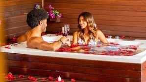Ein Zimmer aus Holz mit Badewanne, Blumen und Rosenblättern.
