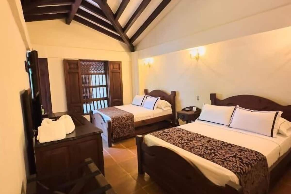 Ein Schlafzimmer mit zwei Betten, einem Deckenventilator und einem Holztisch.