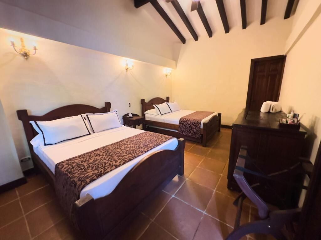 A bedroom with two beds, a desk, and a chair.