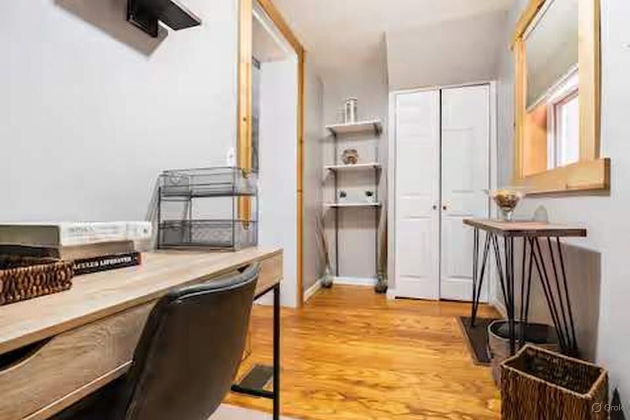 Una cucina compatta con un piano di lavoro in legno, una sedia, un tavolino e uno specchio a parete.