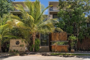 A modern building with a sign reading 'CASA NATURA' surrounded by lush greenery and a bamboo fence. - Casa Natura, Private Plunge w Bikes (Tulum)