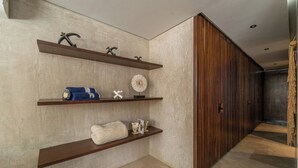 Un couloir avec des étagères en bois où sont exposés divers objets, un mur à texture et un panneau en bois sur le côté droit.